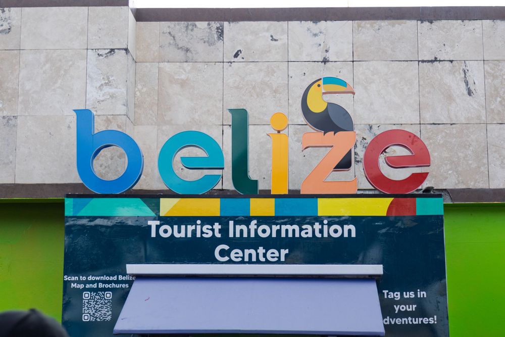 Colorful Belize Tourist Information Center sign on white wall.