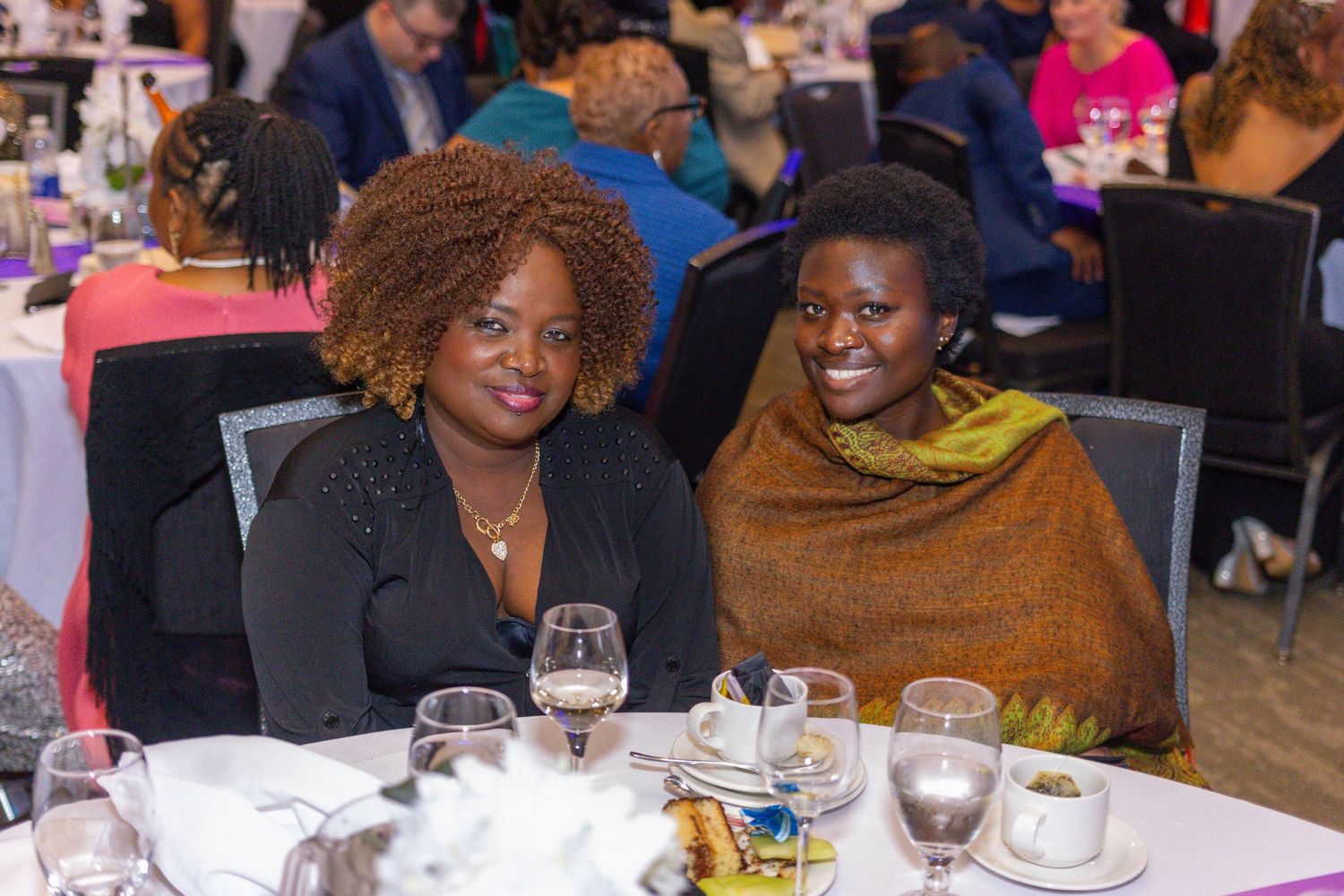 Two people enjoying a formal dinner event at a table with wine glasses and place settings.
