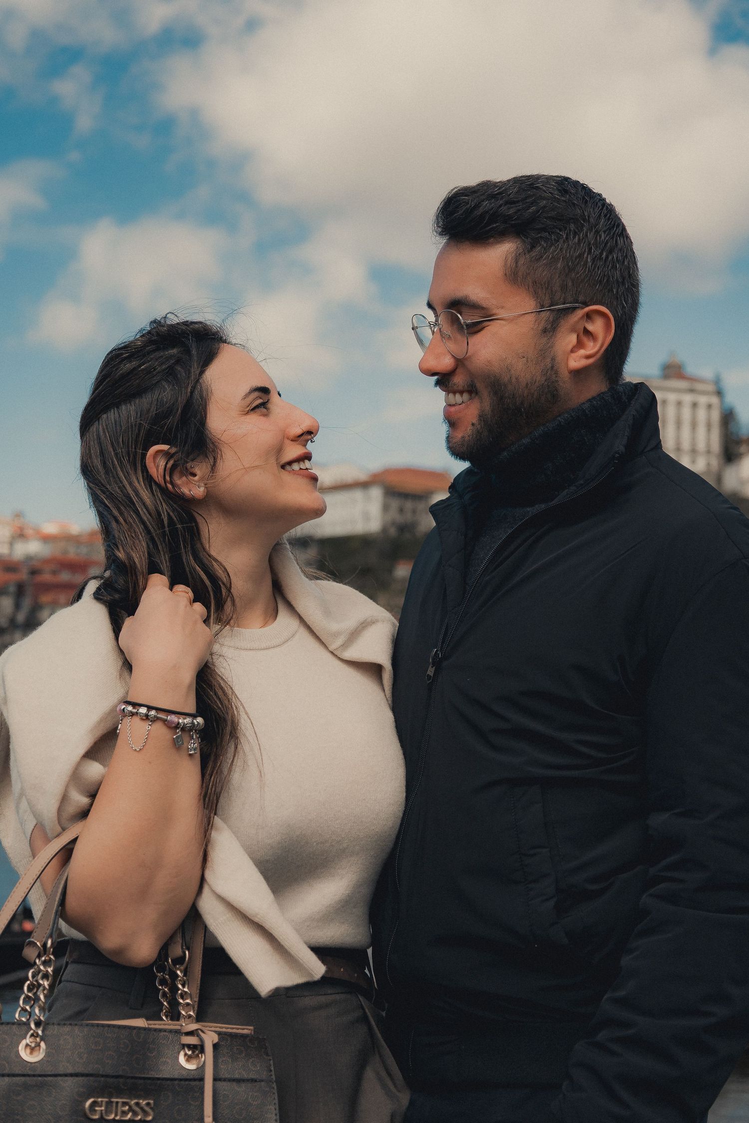 Candid couple photography with natural laughter against cloudy urban backdrop.