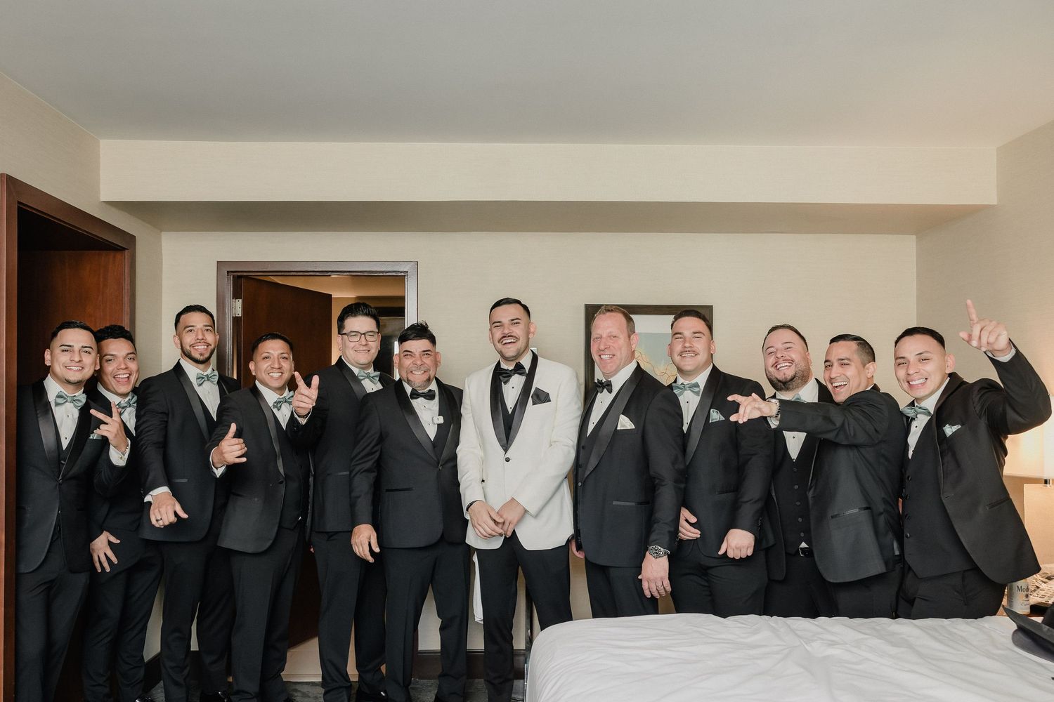 Wedding party in black tuxedos poses in panoramic collage of celebratory group shots.