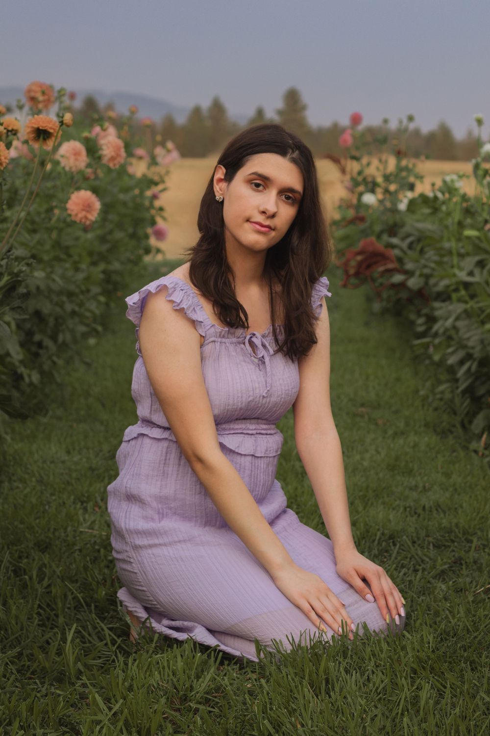 Mead High School graduate, class of 2026. Sitting on knees. posed in the center of dahlias at Simply Picked Flowers in Spokane, WA.