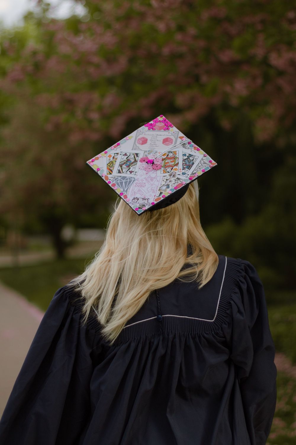 A college graduation cap decorated with a list of previous seven generations of graduates and playing cards.