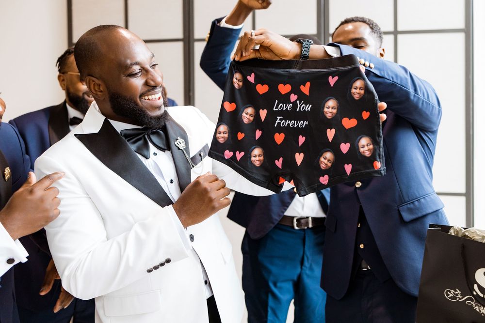 Wedding party members celebrating and holding up a pair of fun novelty underwear with heart patterns during preparation.