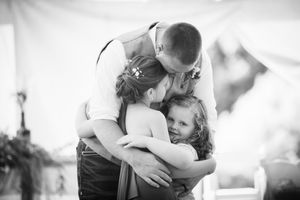 An intimate family embrace during an emotional wedding moment.