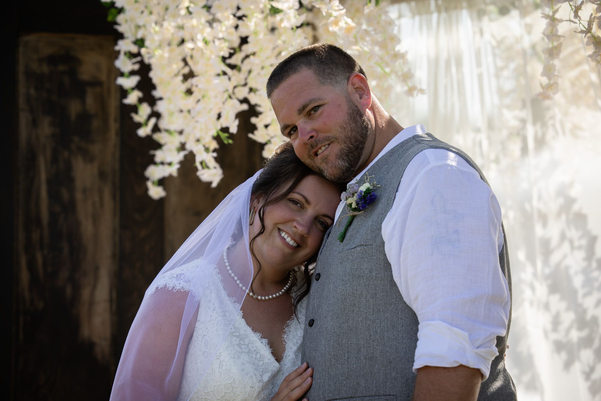 A romantic wedding portrait under hanging floral decorations.