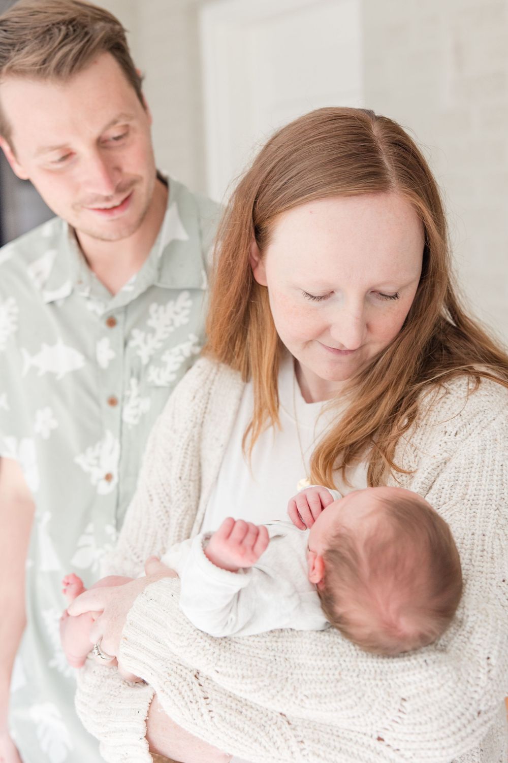 Parents gazing lovingly at their newborn baby wrapped in white clothing.