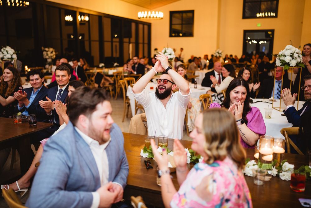 Wedding reception guests celebrate and dance at a lively indoor venue with warm lighting and festive atmosphere.