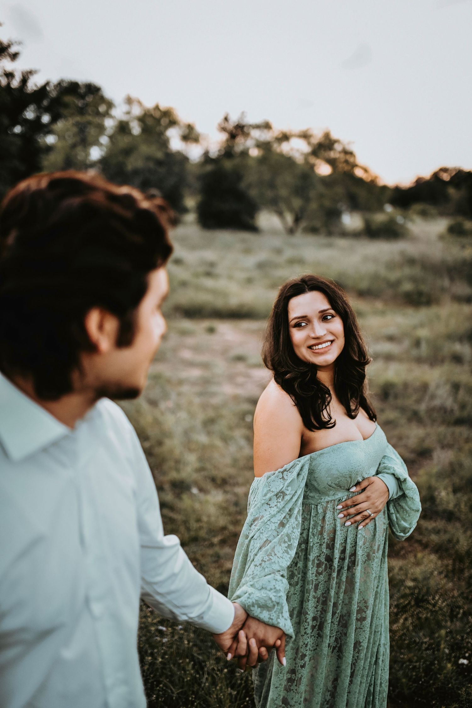 mother looks playfully at her husband as she holds her stomach for her maternity photos at lake grapevine