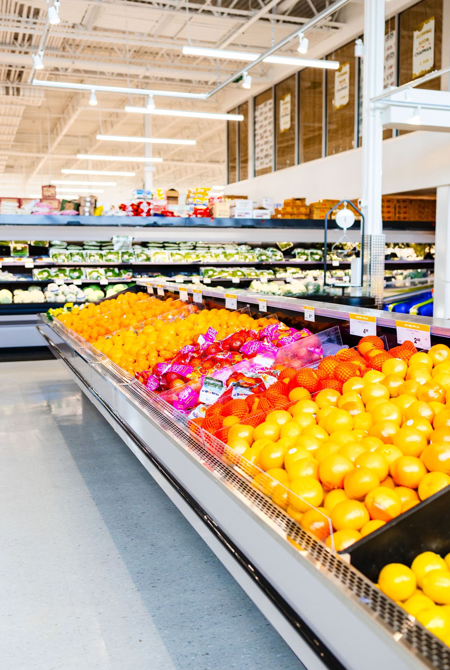 Colorful produce display in grocery store with bright citrus fruits and vegetables.