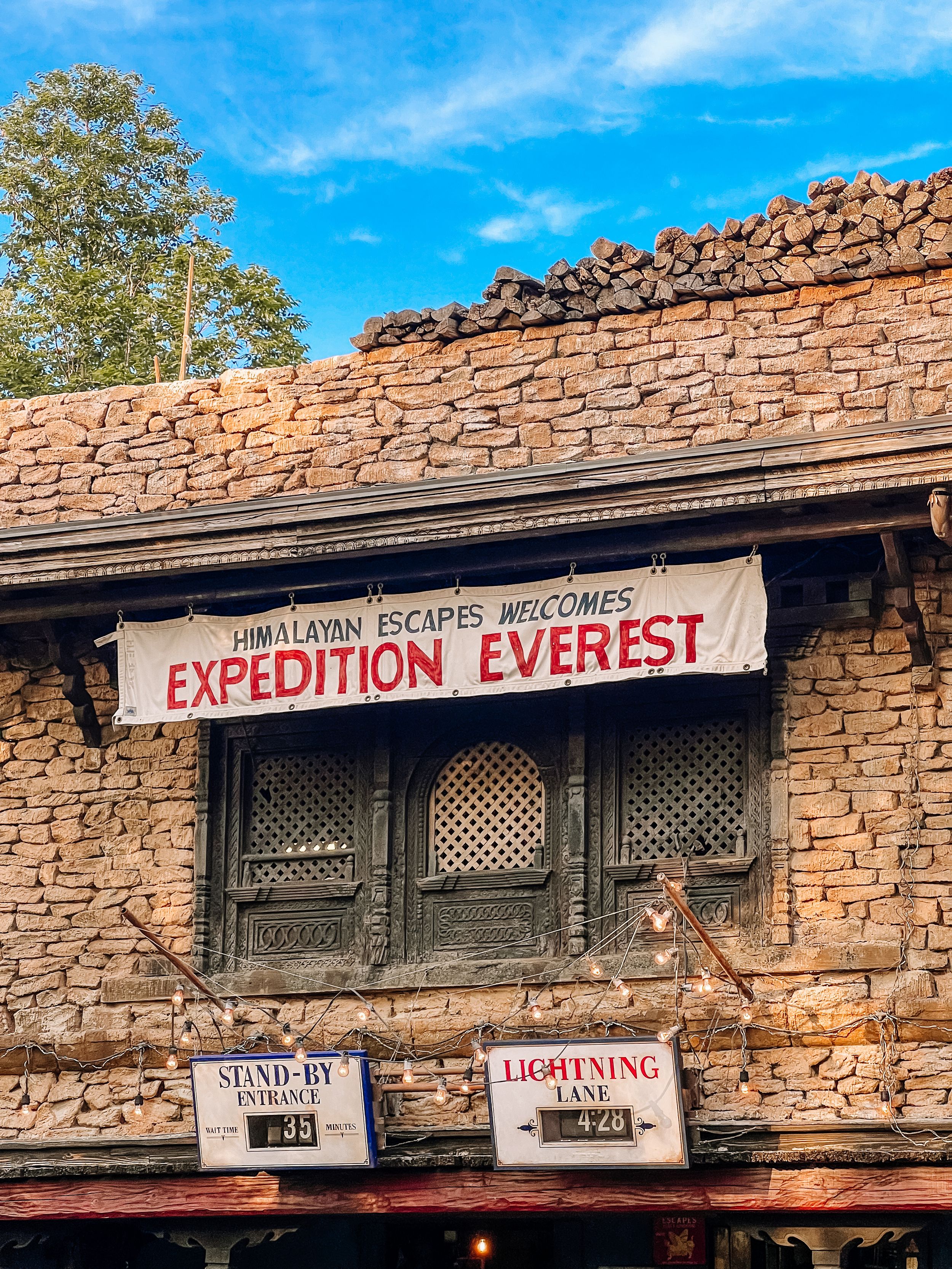 Expedition Everest entrance sign on rustic stone building at Disney's Animal Kingdom theme park with blue sky overhead.