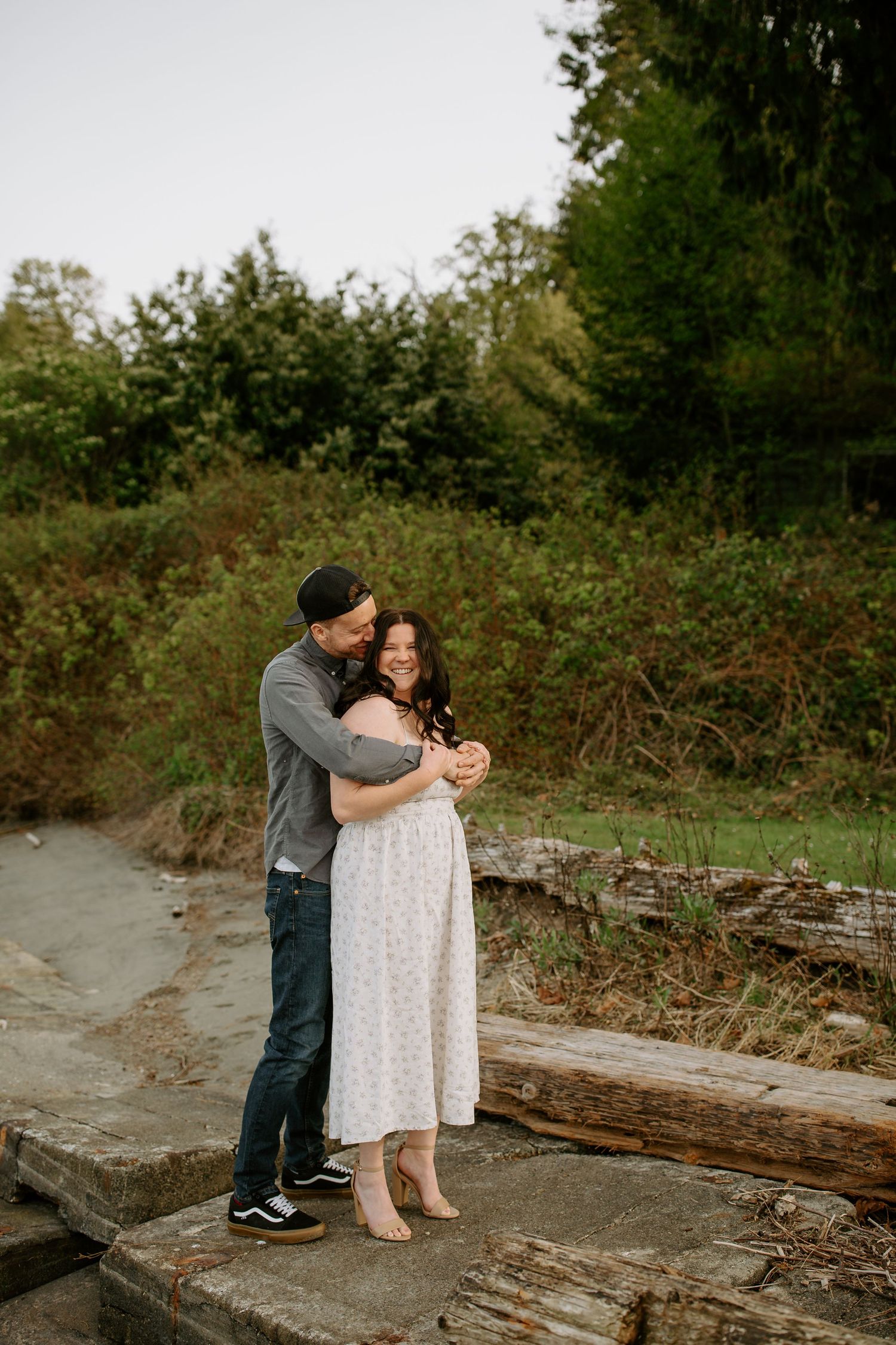 A couple embraces on a wooden bridge surrounded by lush greenery in a romantic outdoor setting.
