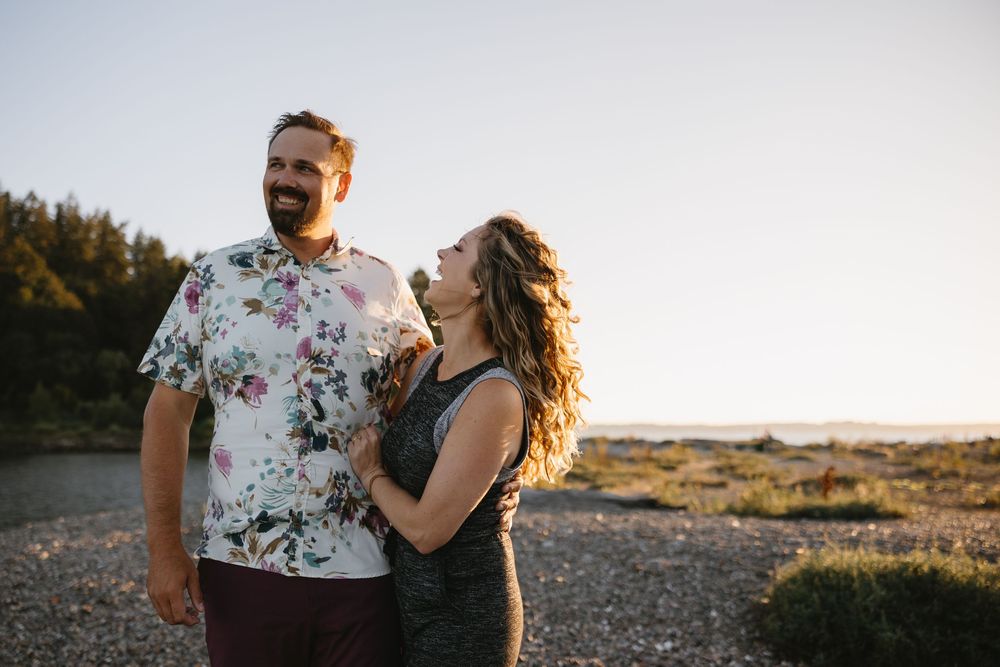 A couple shares a joyful moment together at sunset, with the person in a floral shirt and one in a black top.