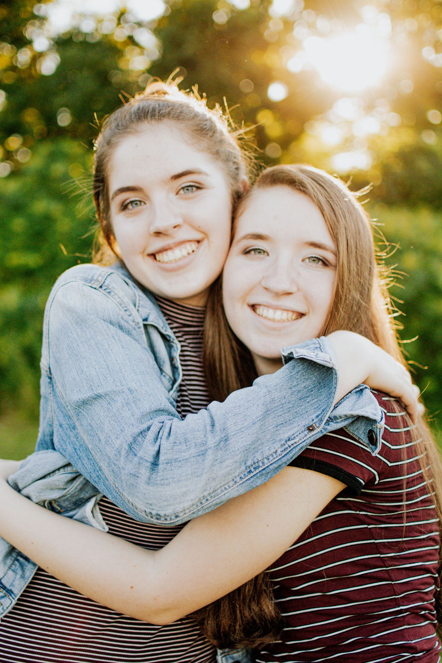 Two sisters hugging and smiling during a golden hour sibling photoshoot.