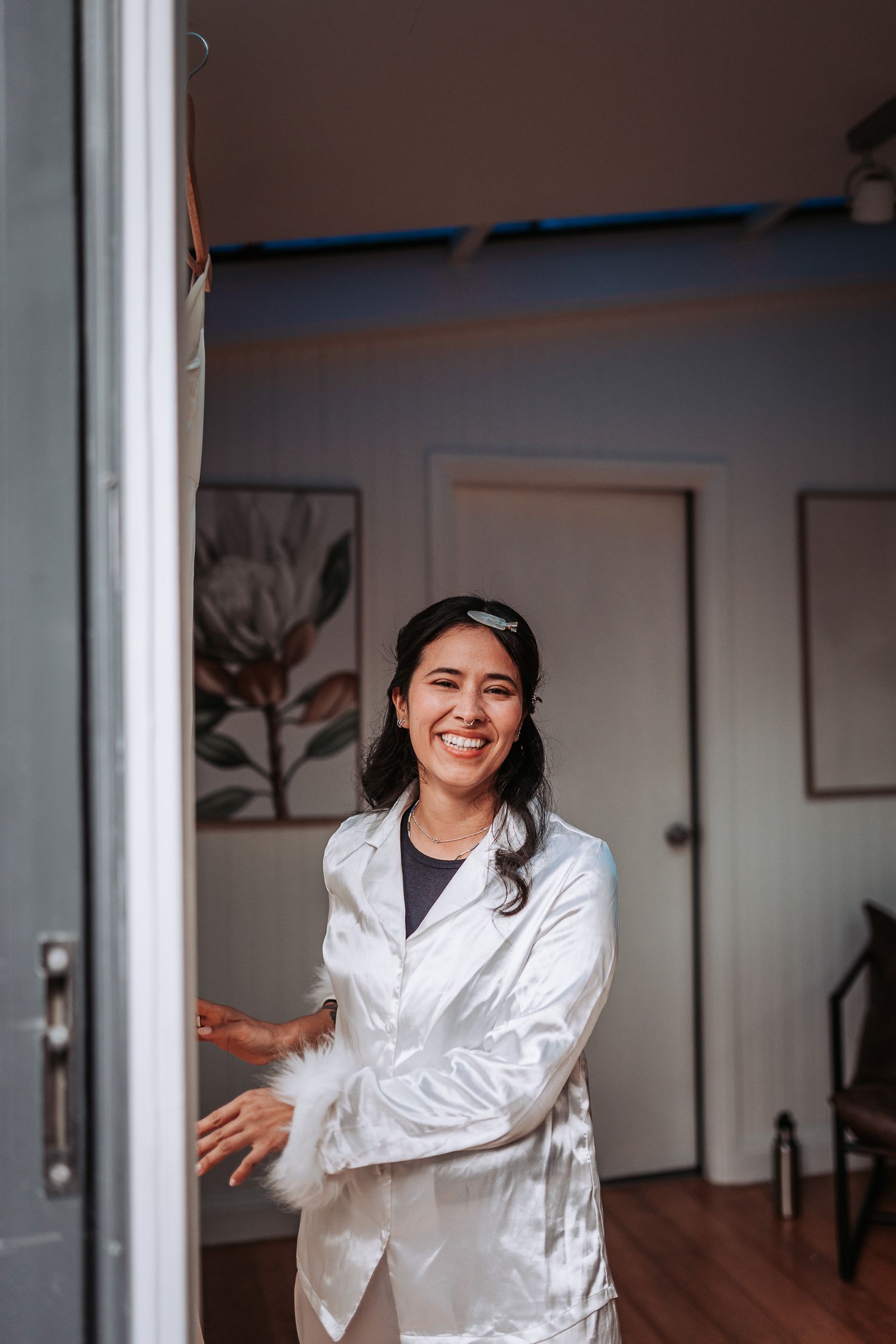 A healthcare professional wearing a white lab coat stands welcomingly in a doorway of a medical office.