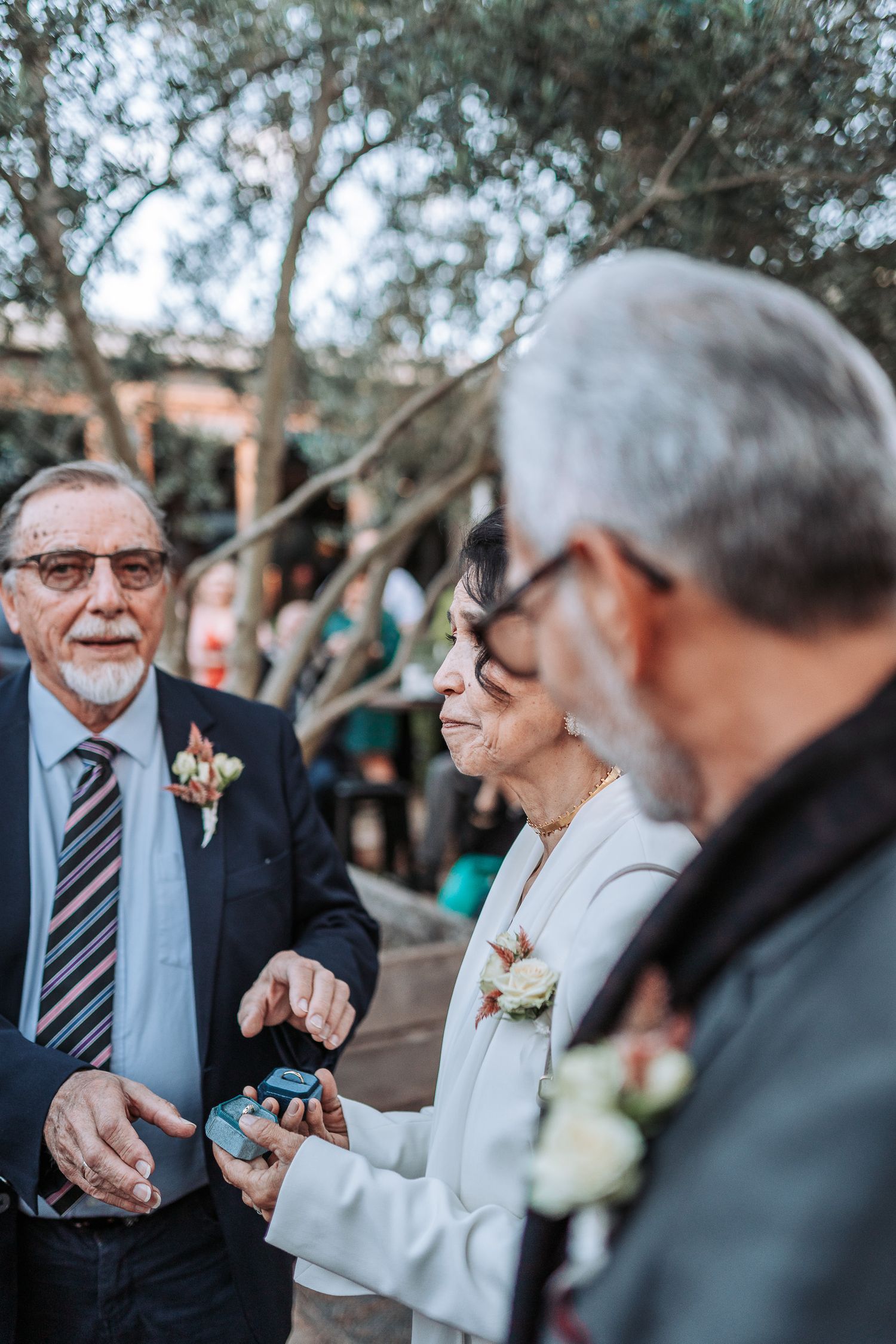 Candid moment at an outdoor wedding reception with guests wearing formal attire and boutonnières.