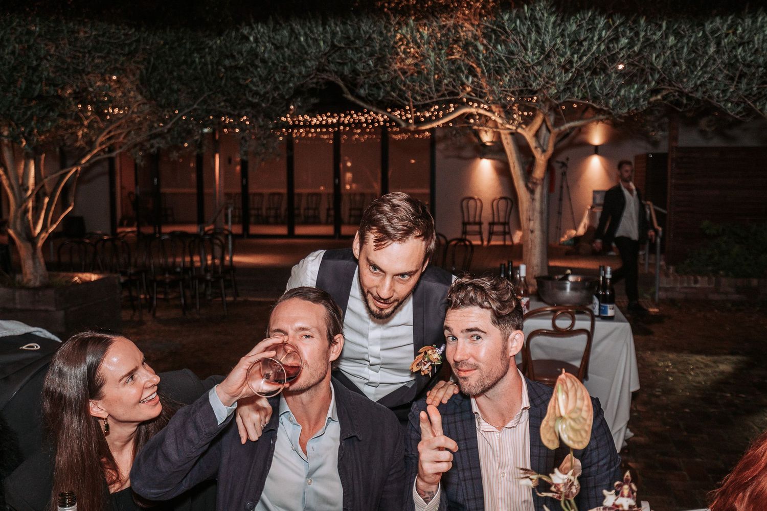 Friends socializing and drinking together at an evening outdoor party with ambient lighting.