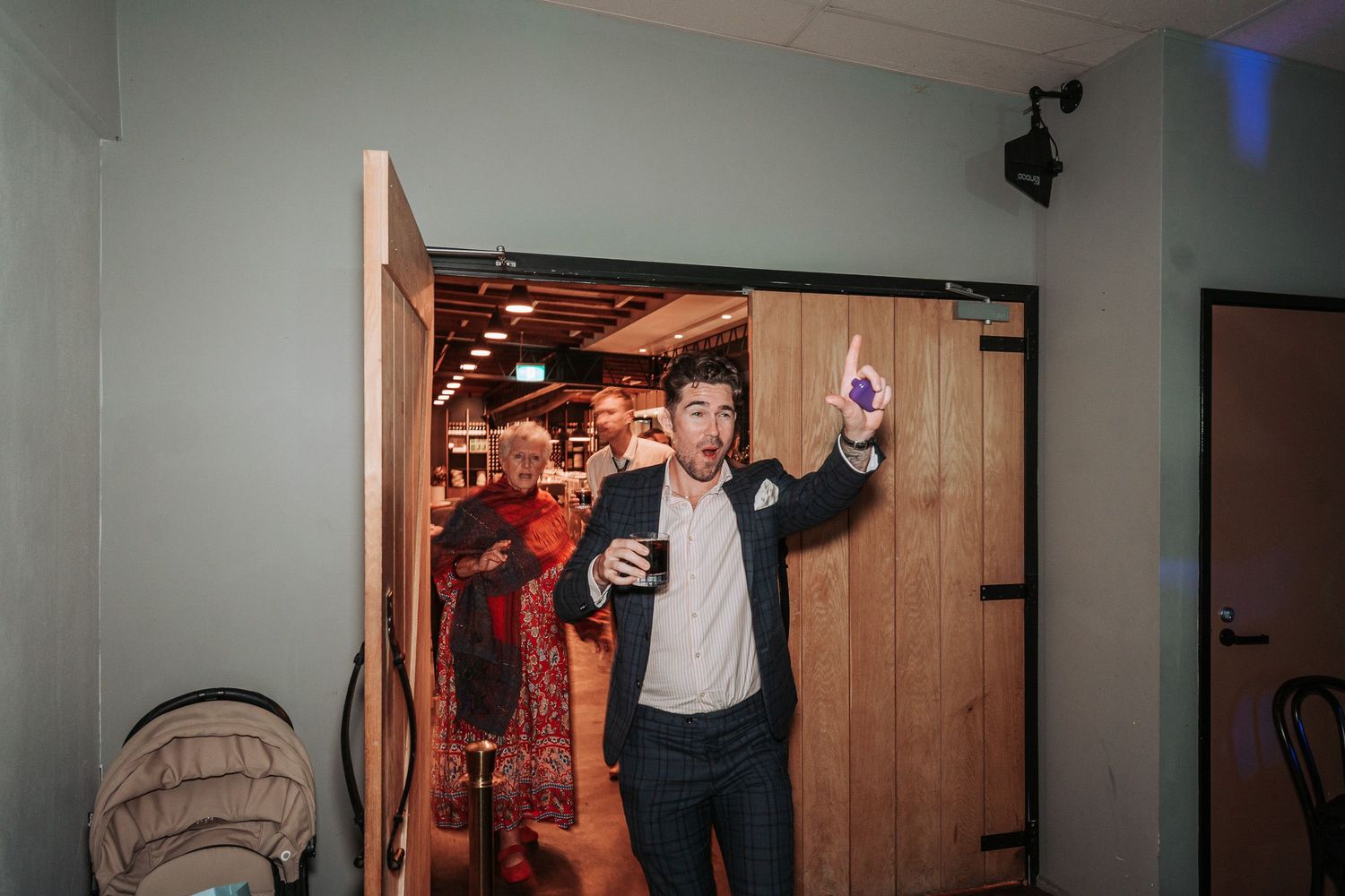 People celebrating with drinks at a wooden-paneled doorway entrance during a festive indoor gathering.