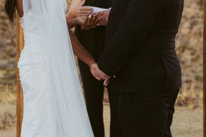 Close up of wedding couple holding hands during outdoor ceremony in desert setting.