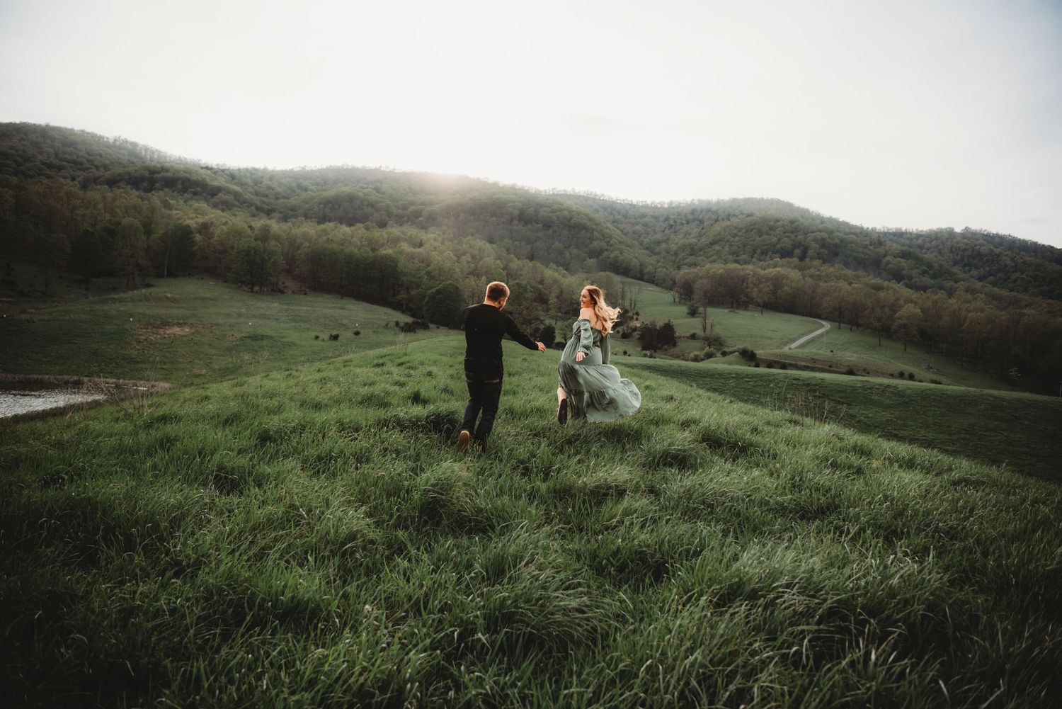 Two figures dancing joyfully on a hilltop meadow at dusk.