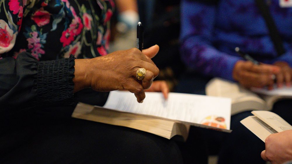 Hands gesture during discussion over papers on a dark surface.