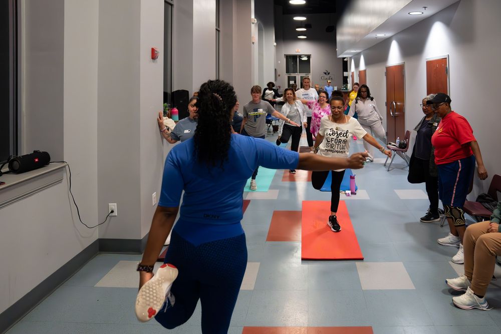 People participate in a physical activity with orange cones in a hallway.