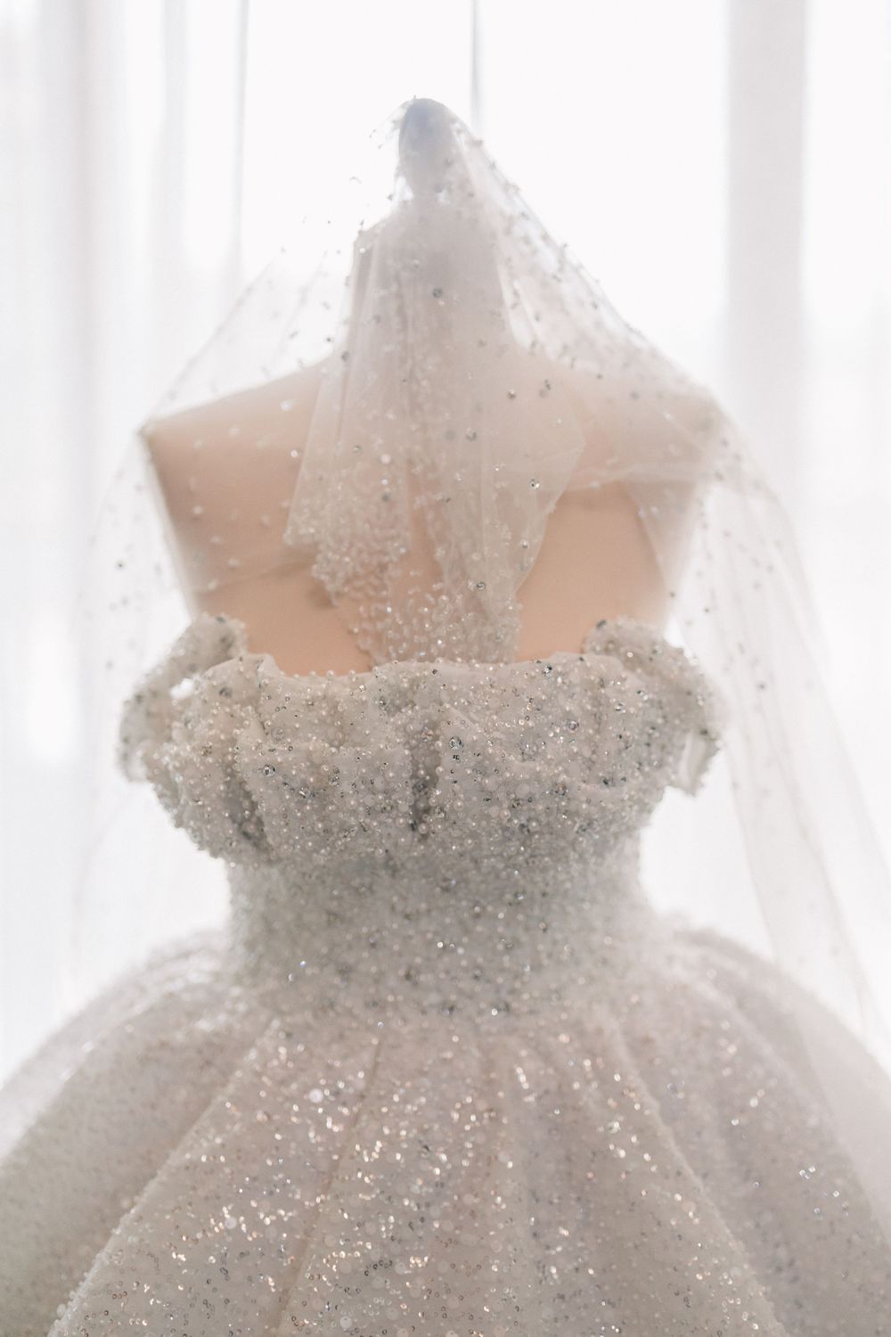 A white sparkly wedding dress with a sweetheart neckline and veil covered in glitter and beading.