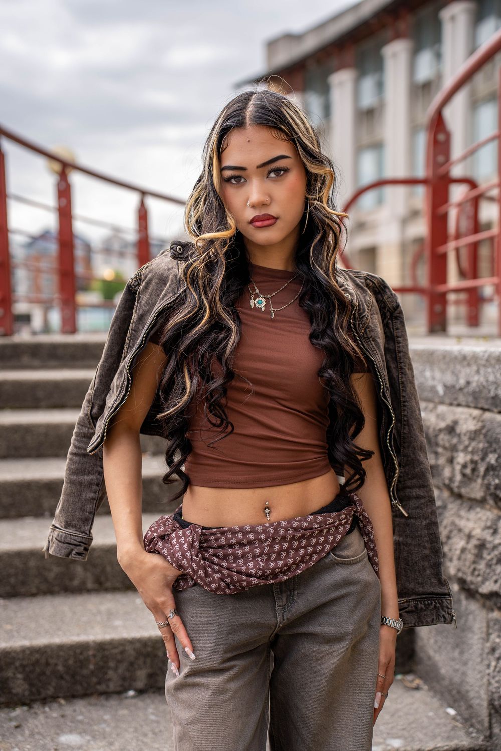 Street style portrait with leather jacket and crop top on concrete steps.