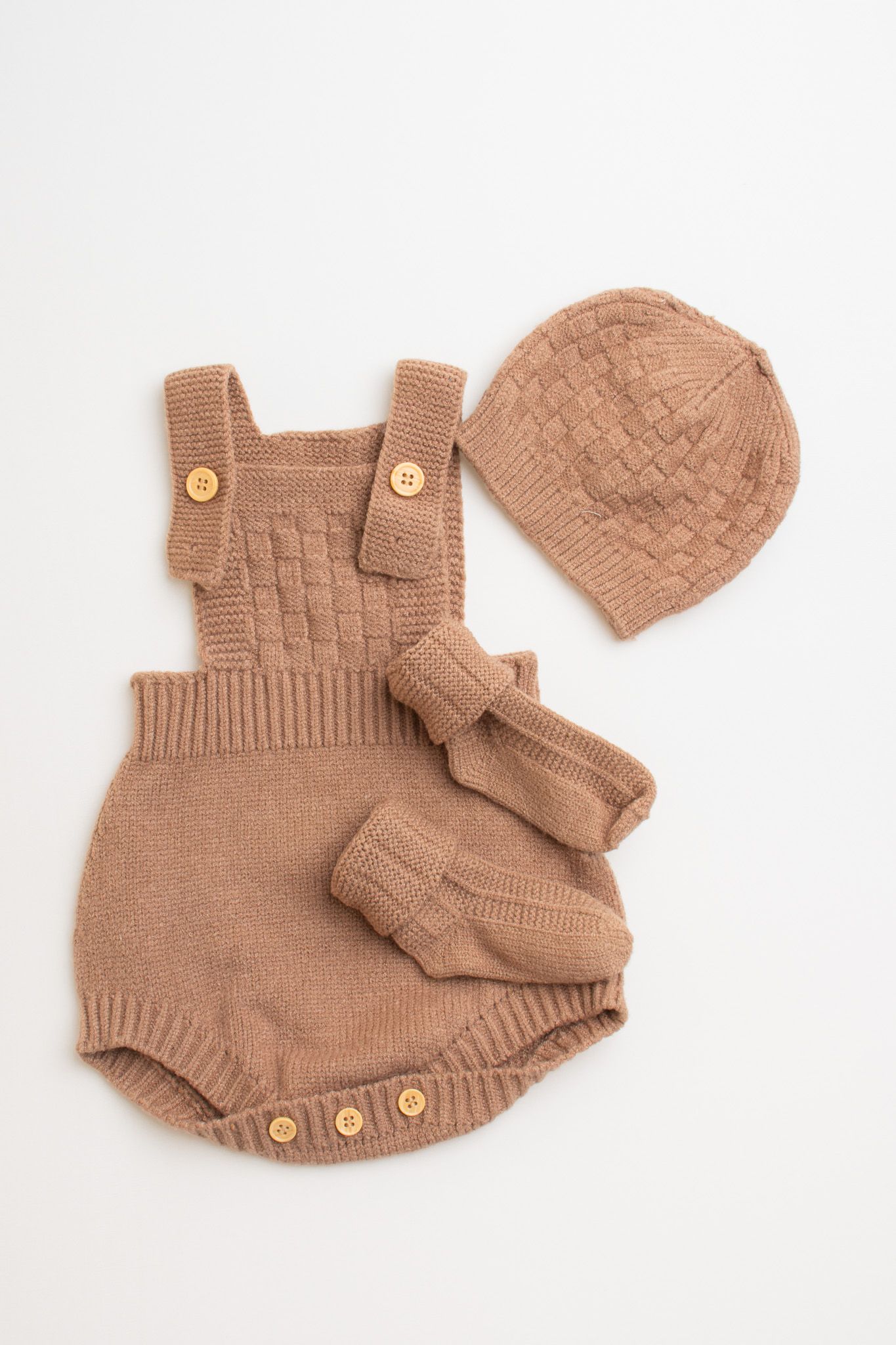 Knitted brown baby romper set with matching beanie hat and booties arranged on white background.