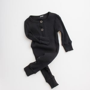 Black ribbed knit baby romper with long sleeves and button details laid flat on white background.