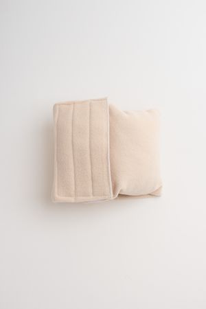 A beige cotton face mask with pleated design lies flat on a white background.