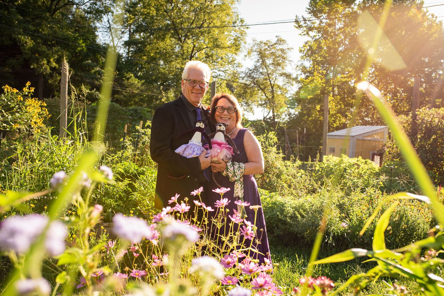 Couple poses among blooming purple wildflowers in garden setting.
