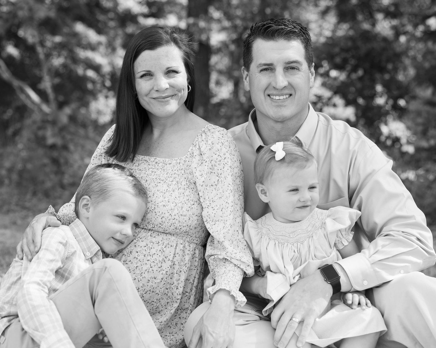 Black and white family portrait featuring parents and two children in coordinated outfits outdoors.
