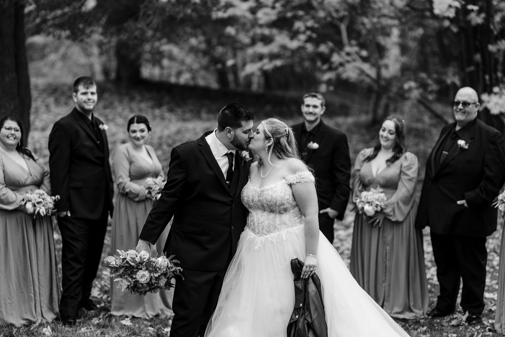 Wedding party laughs together during an outdoor autumn ceremony in black and white.