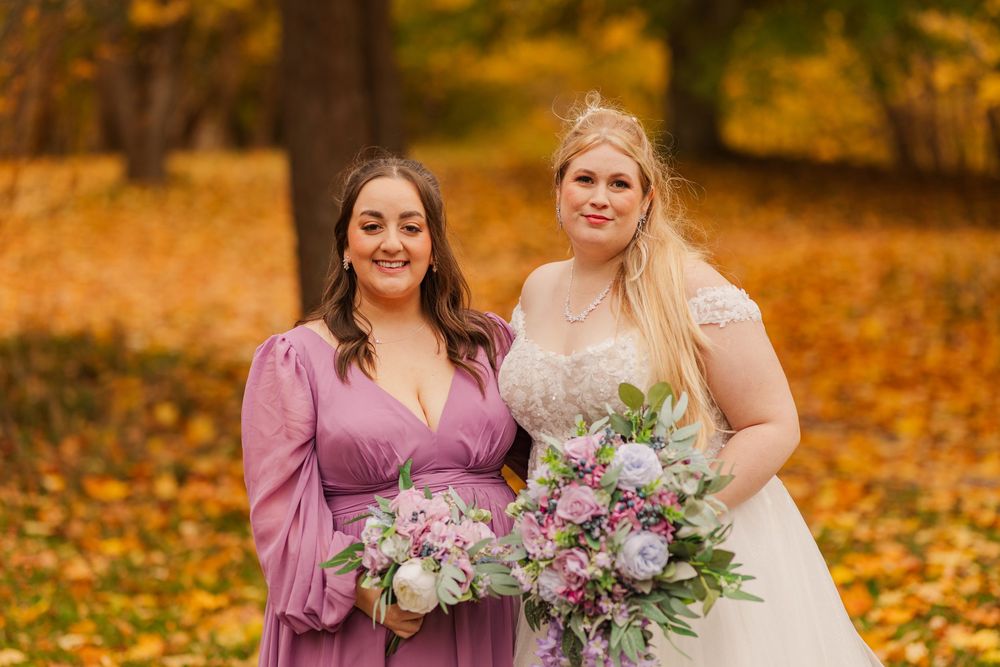 Wedding party poses together in a beautiful autumn forest setting with vibrant orange and yellow fall foliage.