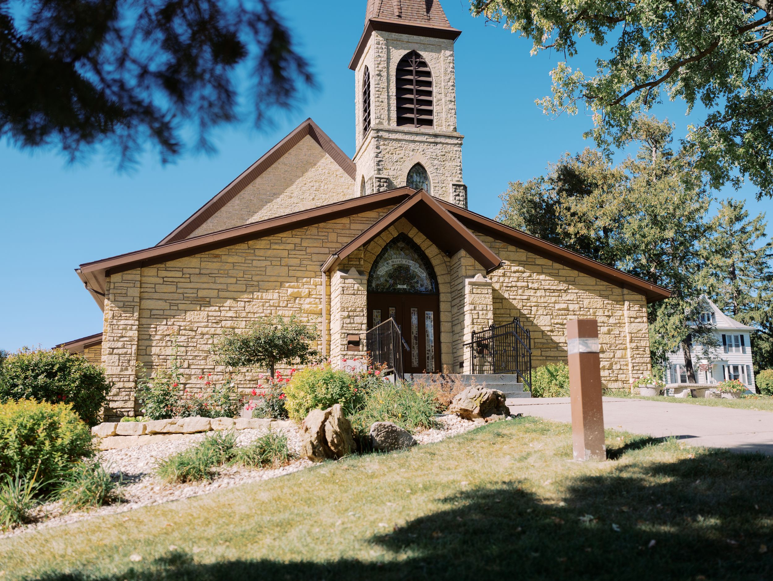 Historic stone church buildings and cemetery nestled on a grassy hillside with trees in the background.