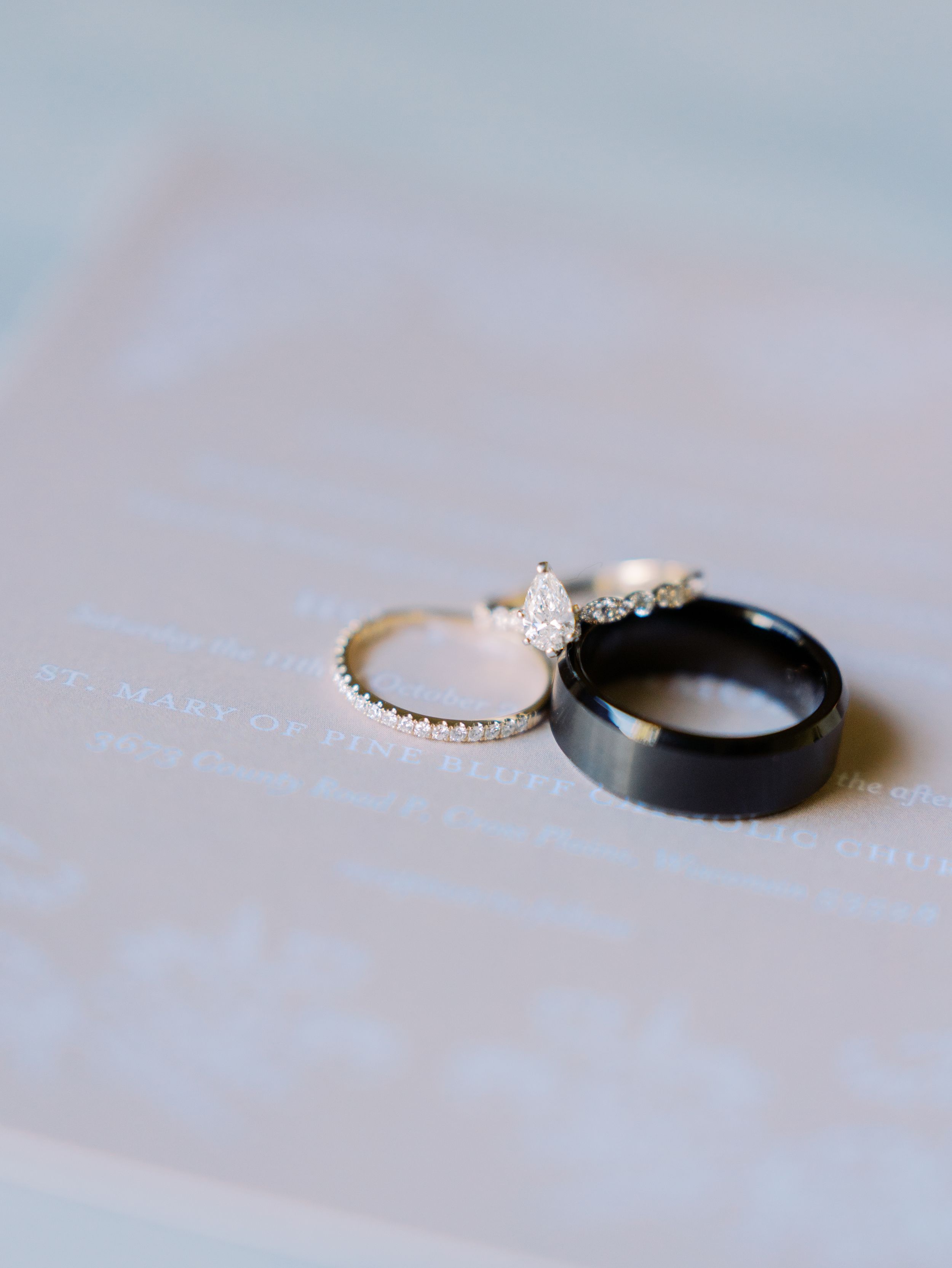 A close-up progression of wedding rings and engagement rings arranged on a soft white textured surface.