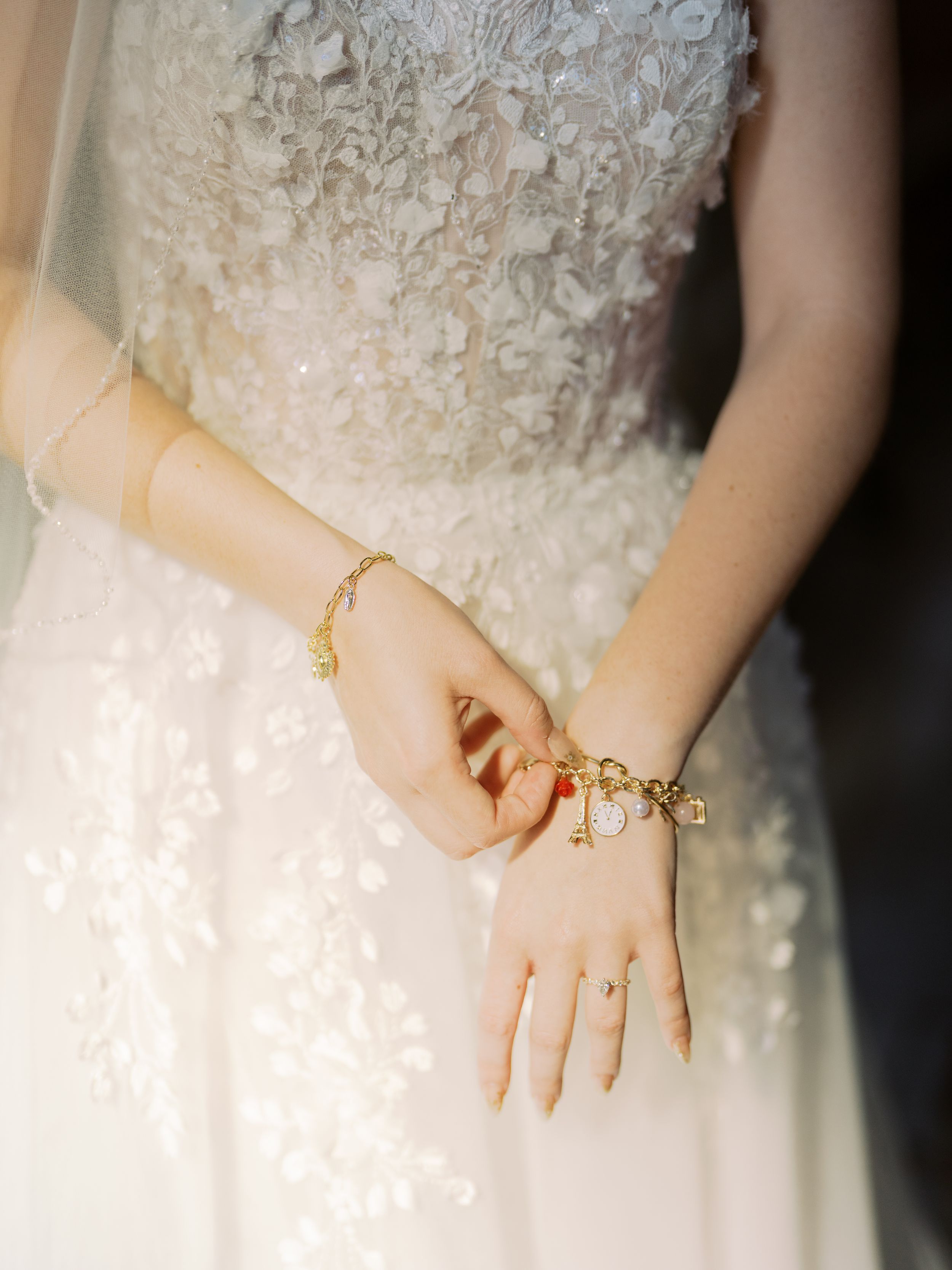 Close-up details of delicate lace wedding dress and gold jewelry accessories in a romantic bridal setting.