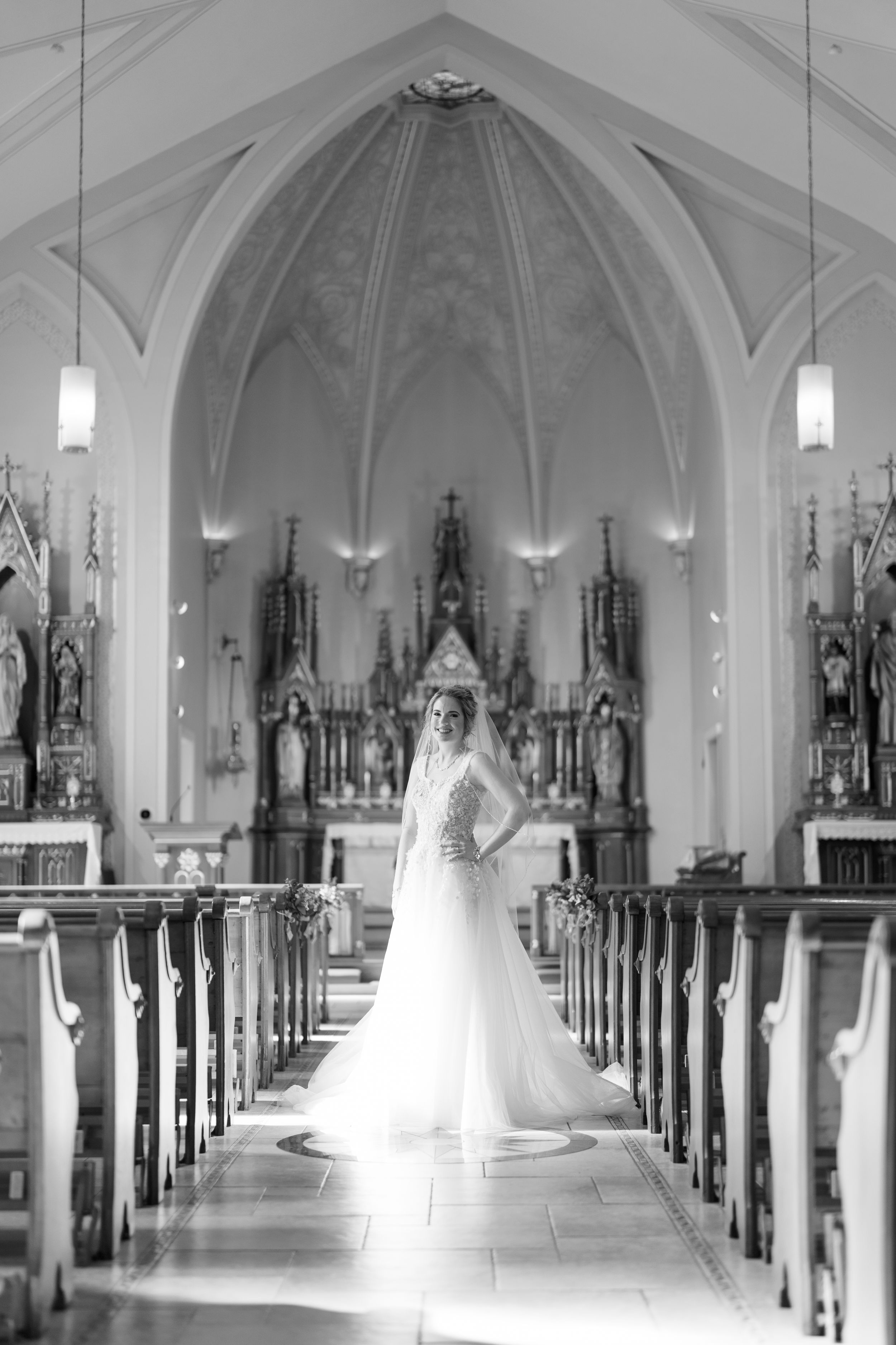 Black and white photo series showing a bride in a flowing white dress posing in the aisle of a grand cathedral church interior.