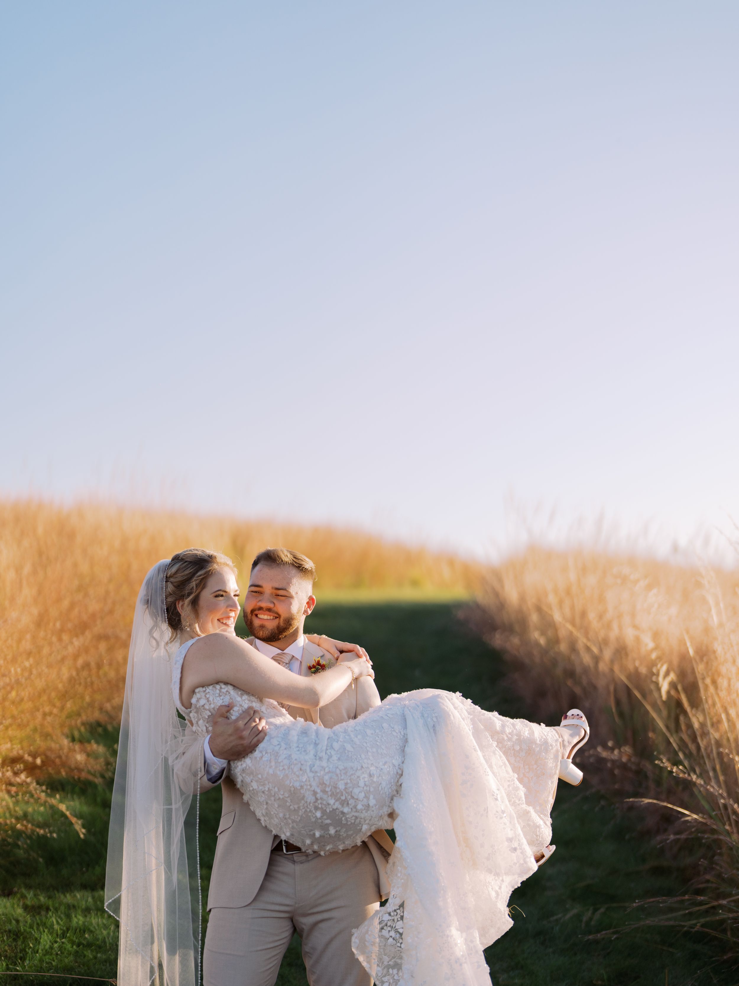 Romantic wedding couple embraces in a golden wheat field at sunset creating a dreamy silhouette.