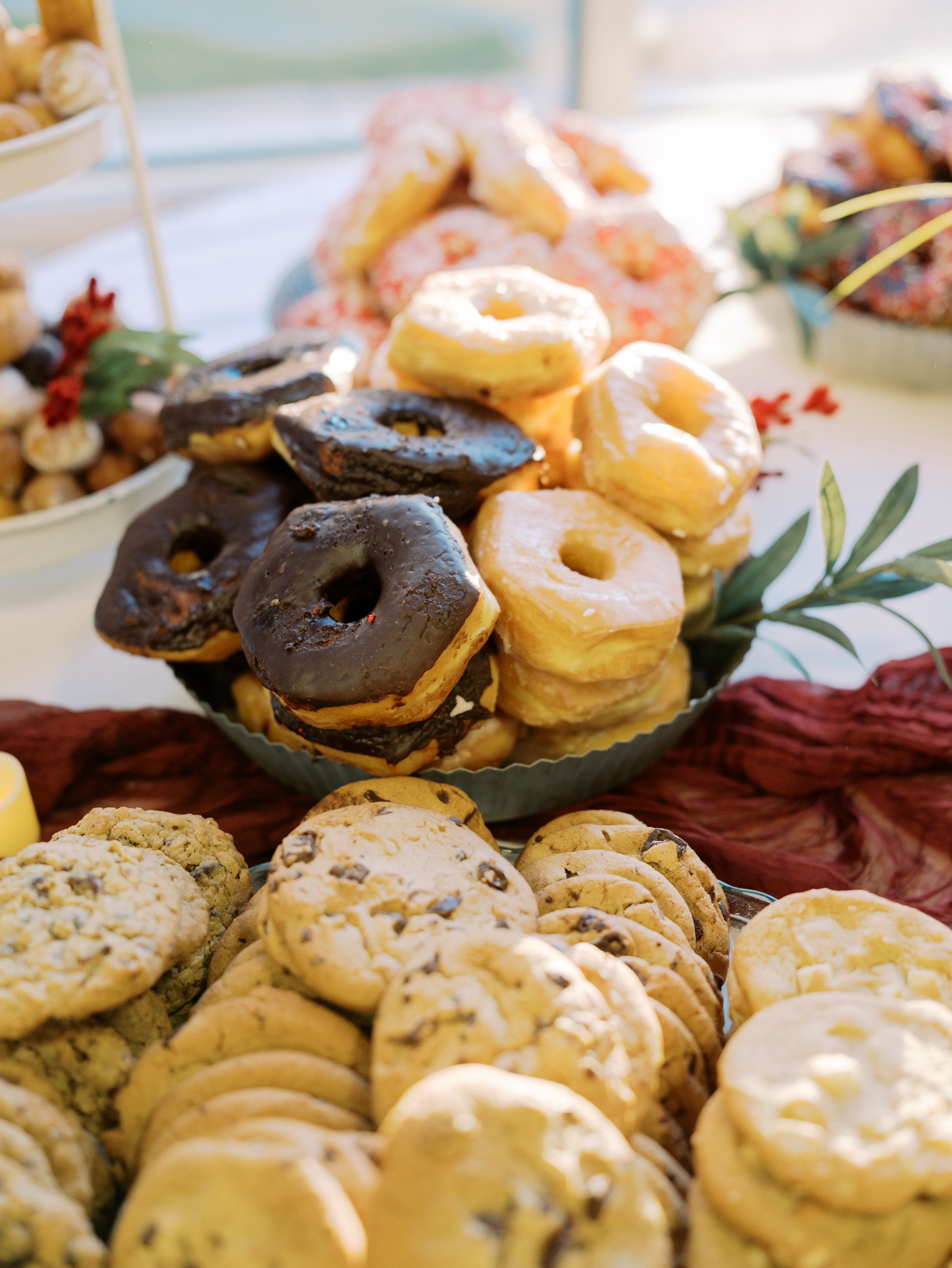 An assortment of chocolate and glazed donuts alongside chocolate chip cookies displayed on a dessert platter.