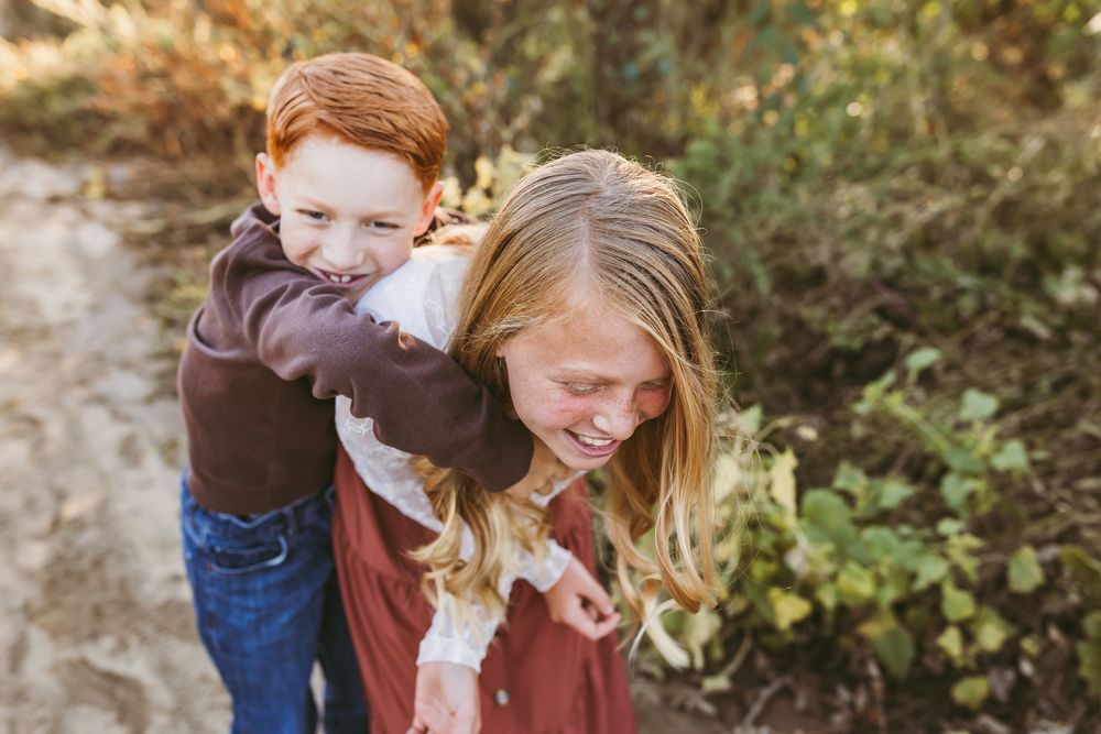 Candid outdoor family photoshoot with playful interactions in natural desert setting at golden hour.