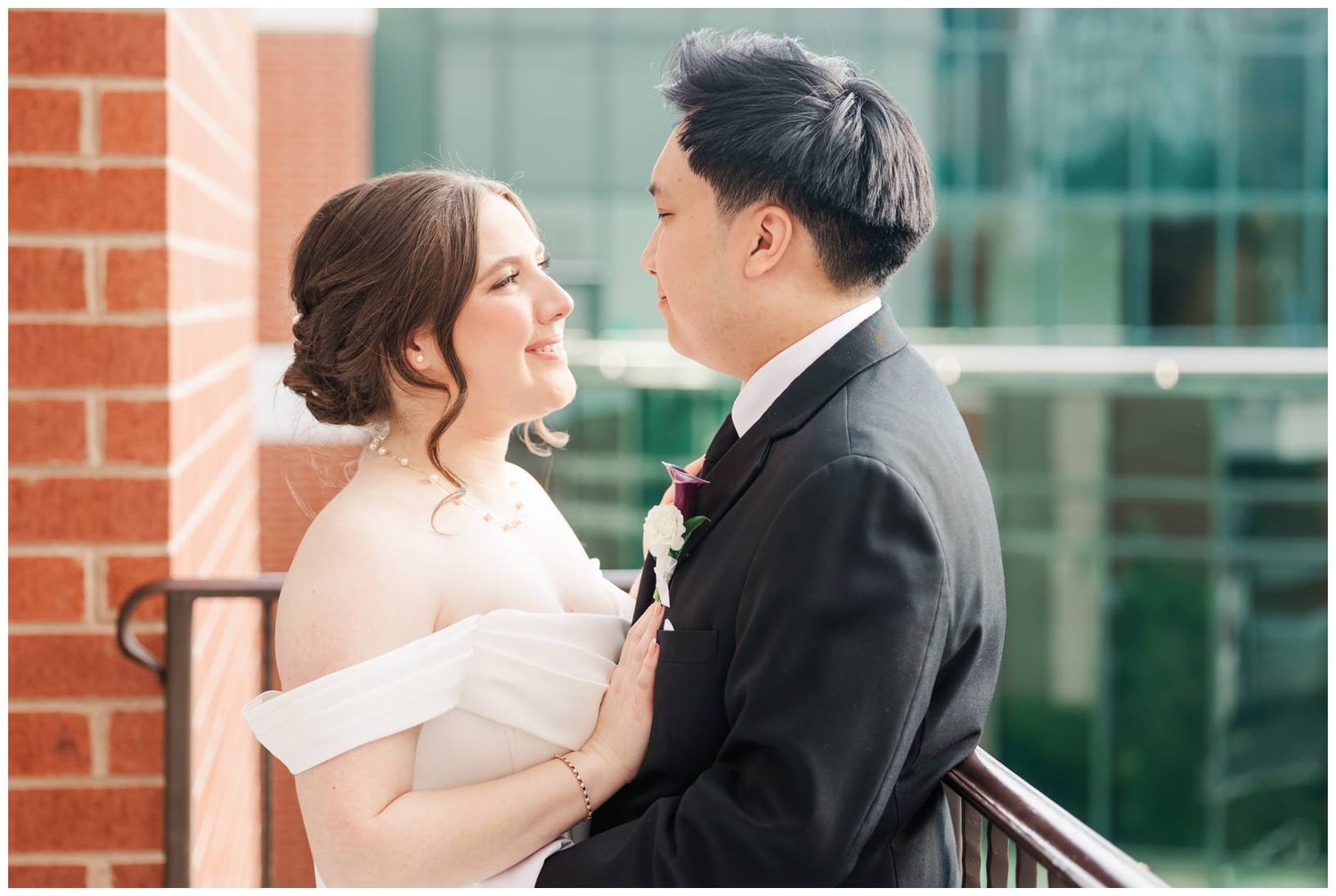 Romantic wedding portraits taken outdoors against a modern brick and glass building backdrop.