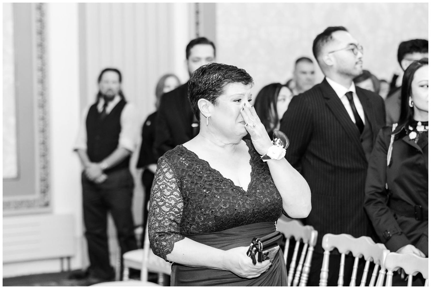 Wedding guests seated in formal attire during indoor ceremony celebration.