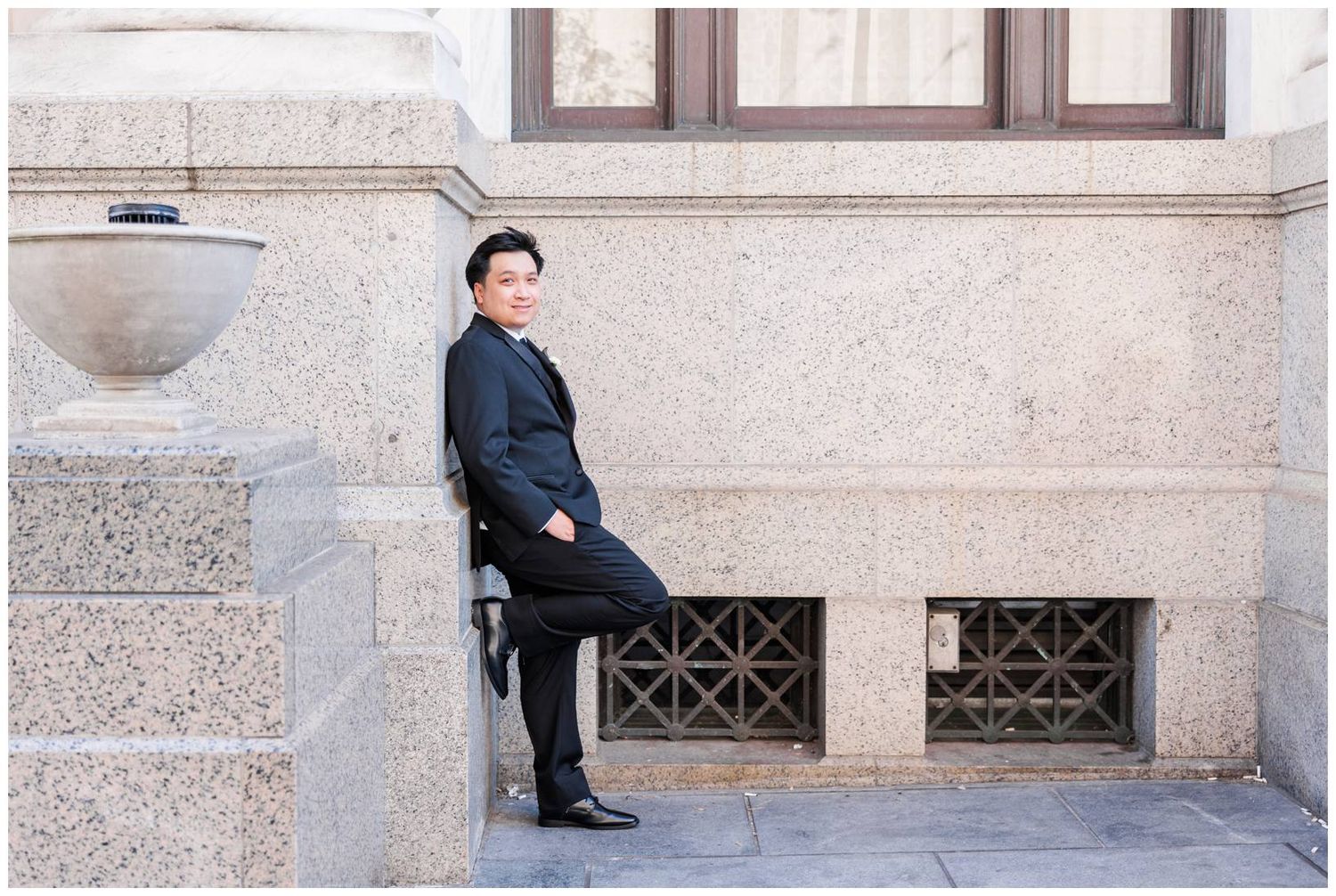 Formal wedding portraits taken along stone building with architectural details.