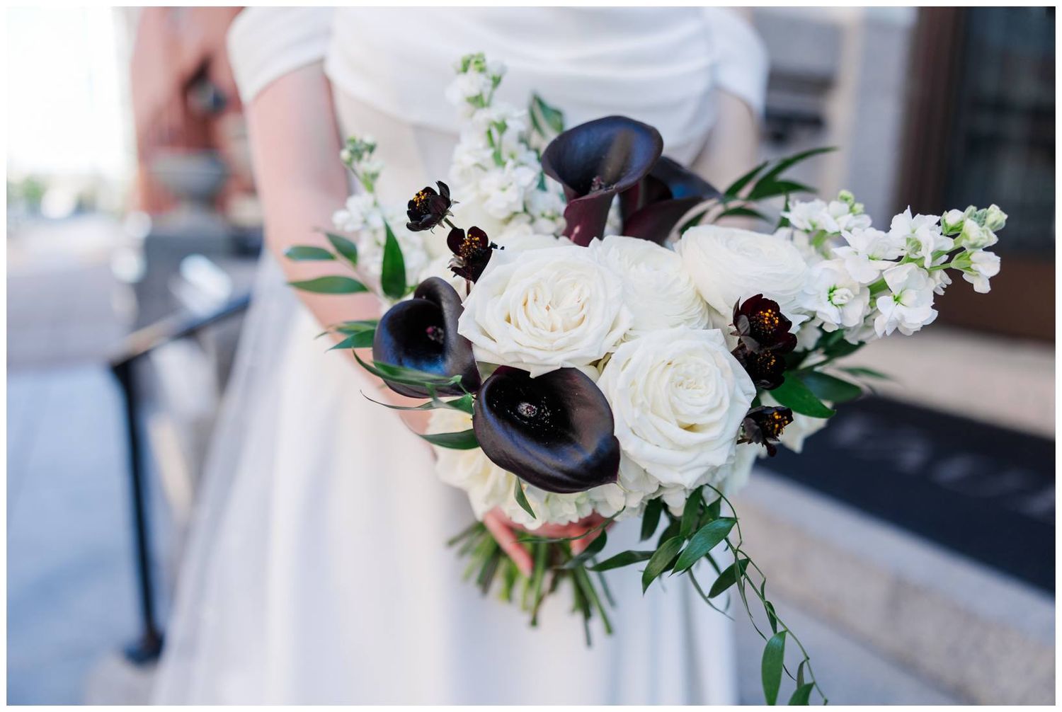 Elegant white and black floral bouquets with roses and greenery displayed at a formal event.