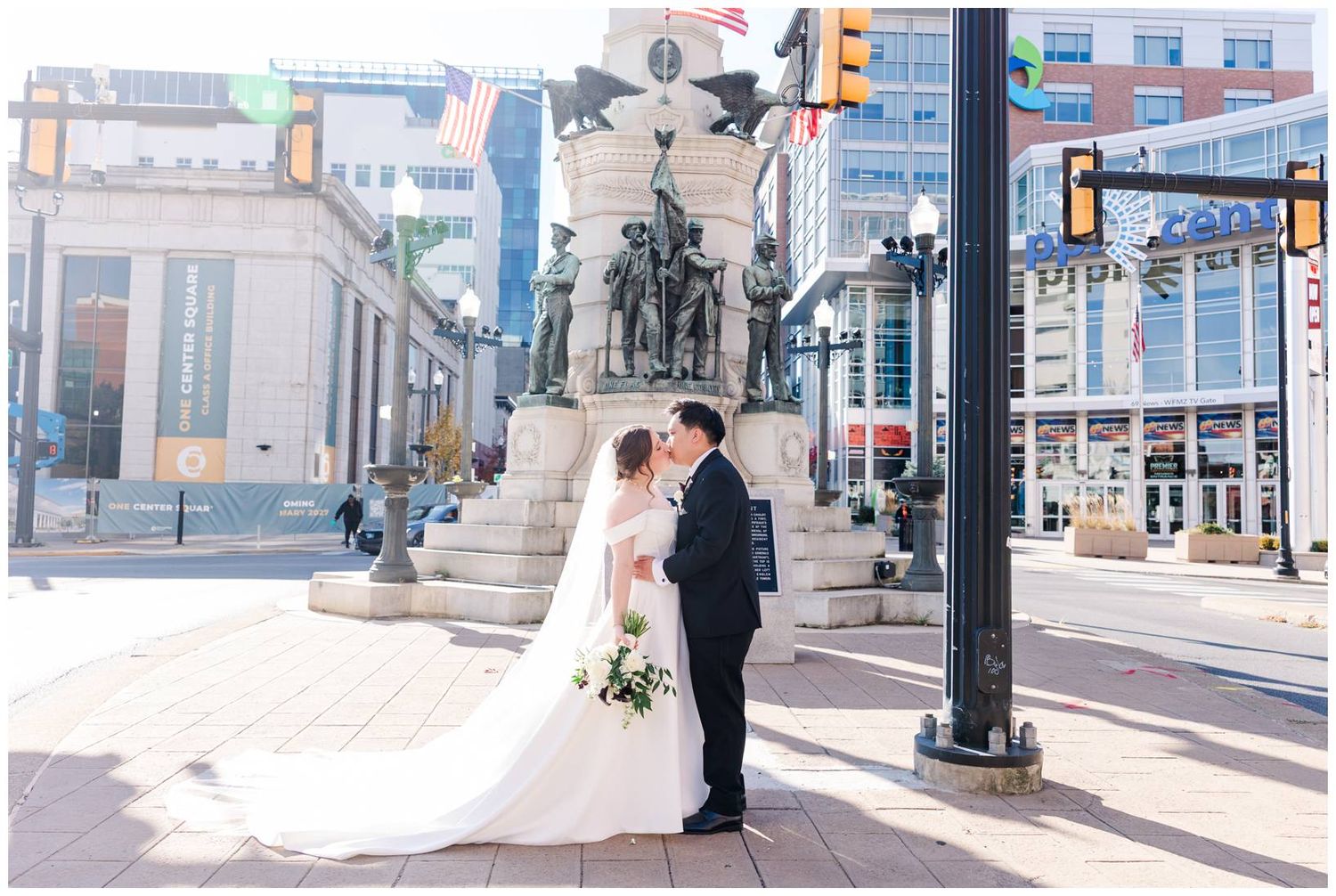 Wedding ceremony participants gather on city steps with downtown buildings and traffic lights in background.