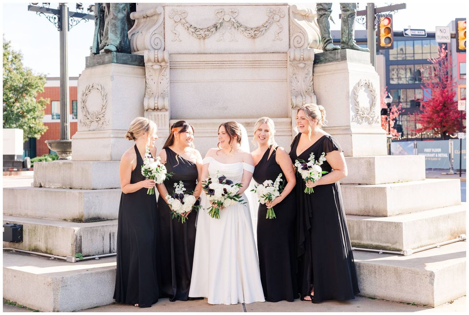 Wedding party poses on elegant stone steps in an urban setting with black and white formal attire.