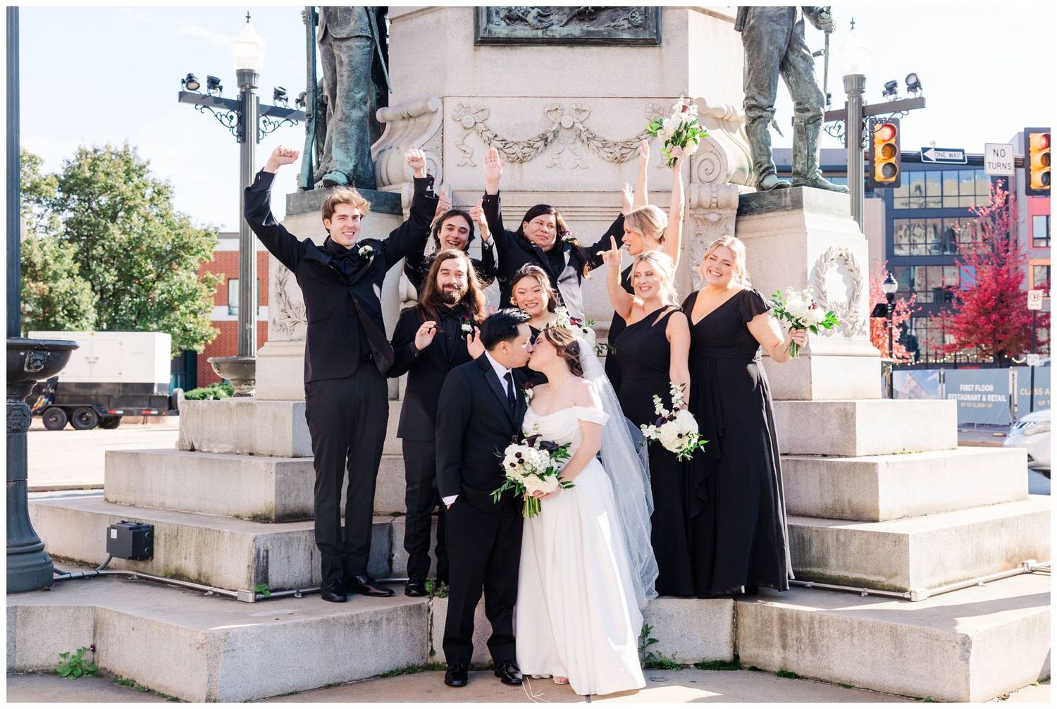 Wedding party celebrates joyfully on stone steps outdoors.