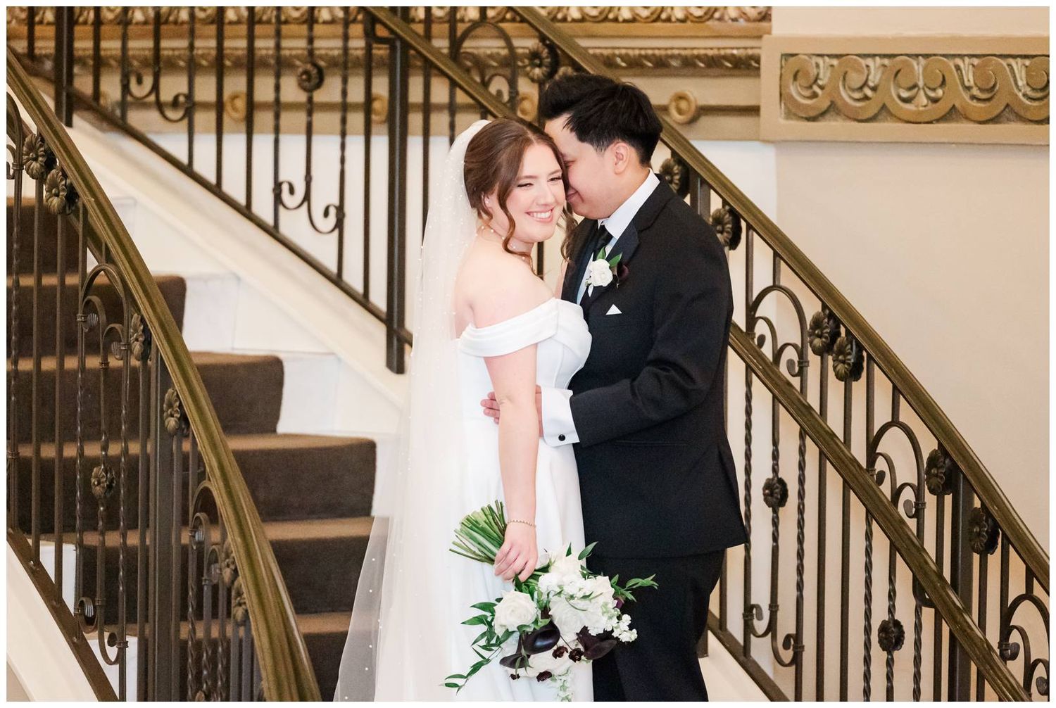 Wedding couple sharing intimate moments along an ornate staircase with wrought iron details.