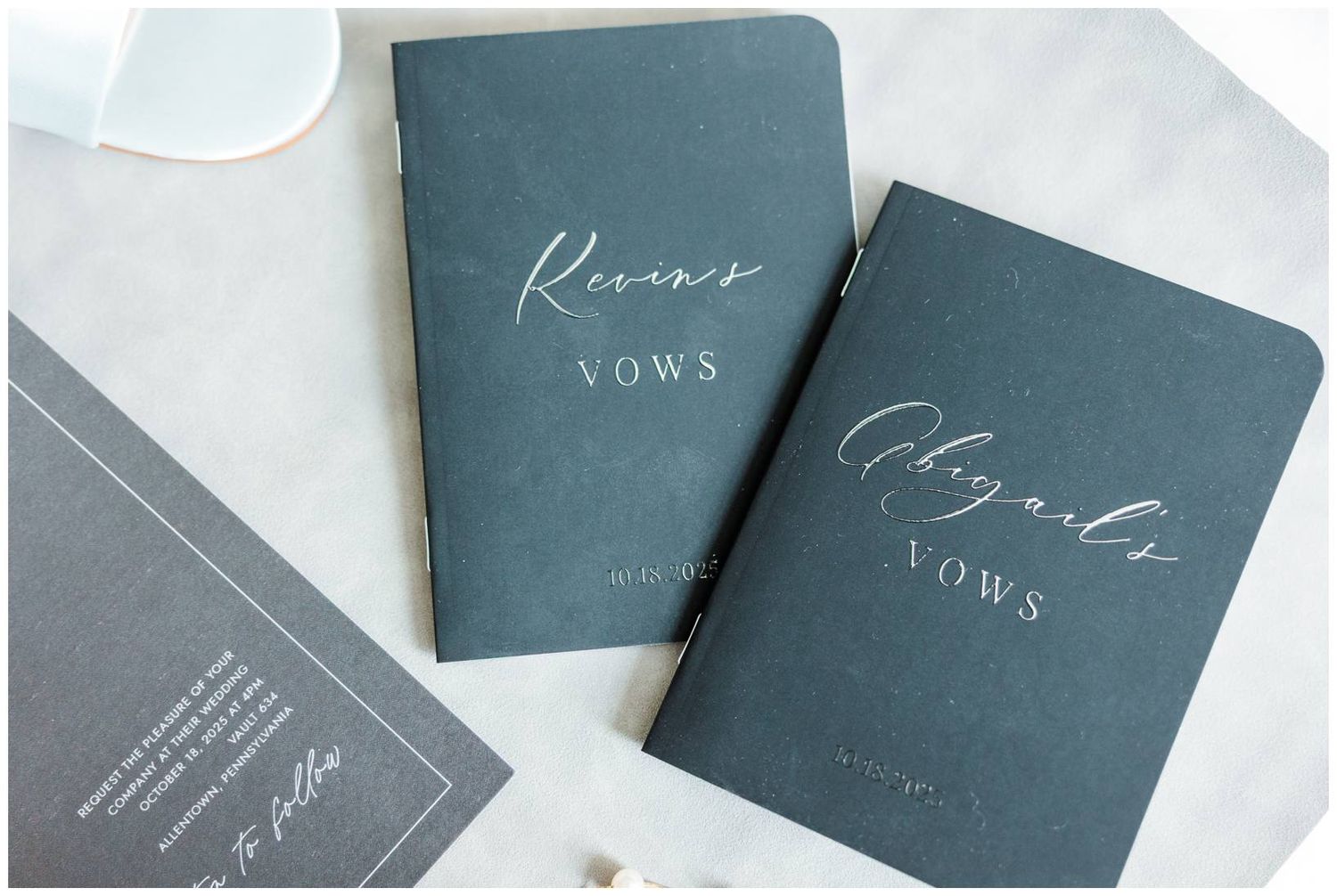 Elegant dark green wedding stationery with white calligraphy text arranged on a light marble surface.